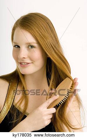 Portrait of a young woman brushing her hair and smiling View Large Photo Image Stock Photography - Portrait of a young woman brushing her hair and smiling. Fotosearch