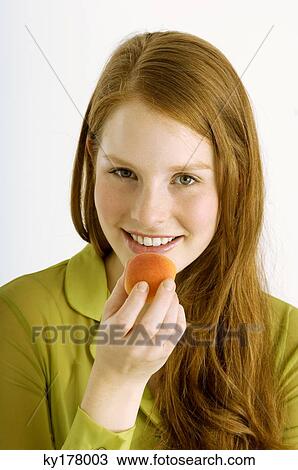 Portrait of a young woman eating an apricot and smiling View Large Photo Image Stock Image - Portrait of a young woman eating an apricot and smiling. Fotosearch