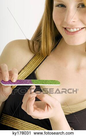 Portrait of a young woman filing her nails and smiling View Large Photo Image Stock Image - Portrait of a young woman filing her nails and smiling. Fotosearch