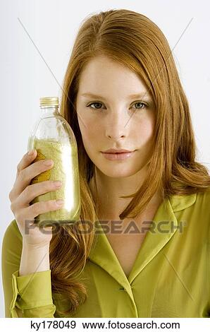 Stock Photo - Portrait of a young woman holding a bottle of aromatherapy oil. Fotosearch