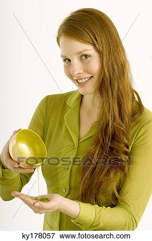 Stock Photo - Portrait of a young woman pouring massage oil on her palm. Fotosearch