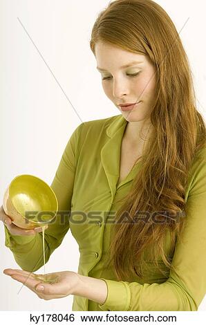 Stock Photograph - Young woman pouring massage oil on her palm. Fotosearch