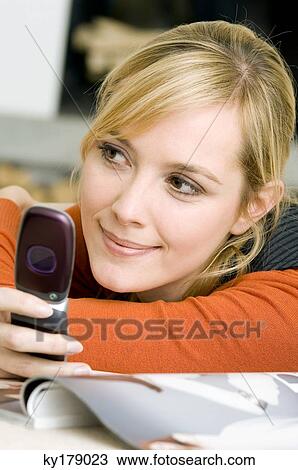 Close-up of a young woman using a mobile phone and smiling View Large Photo Image Stock Image - Close-up of a young woman using a mobile phone and smiling. Fotosearch