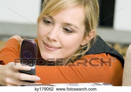 Close-up of a young woman using a mobile phone and smiling View Large Photo Image Stock Image - Close-up of a young woman using a mobile phone and smiling. Fotosearch