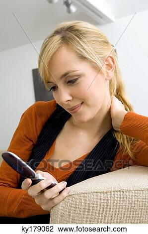 Close-up of a young woman using a mobile phone and smiling View Large Photo Image Stock Image - Close-up of a young woman using a mobile phone and smiling. Fotosearch