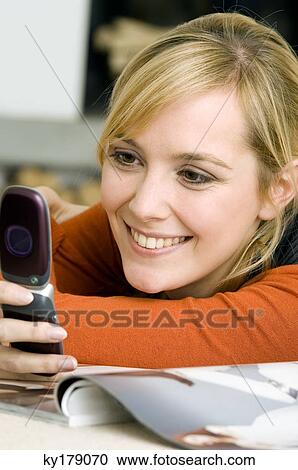 Close-up of a young woman using a mobile phone and smiling View Large Photo Image Stock Image - Close-up of a young woman using a mobile phone and smiling. Fotosearch