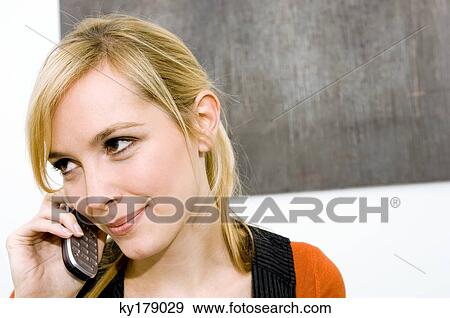 Close-up of a young woman using a mobile phone and smiling View Large Photo Image Stock Photo - Close-up of a young woman using a mobile phone and smiling. Fotosearch