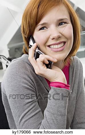 Close-up of a young woman using a mobile phone and smiling View Large Photo Image Stock Photograph - Close-up of a young woman using a mobile phone and smiling. Fotosearch