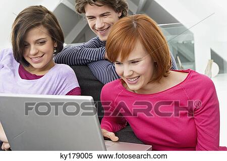 Close-up of two young women and a teenage boy looking at a laptop View Large Photo Image Stock Photography - Close-up of two young women and a teenage boy looking at a laptop. Fotosearch