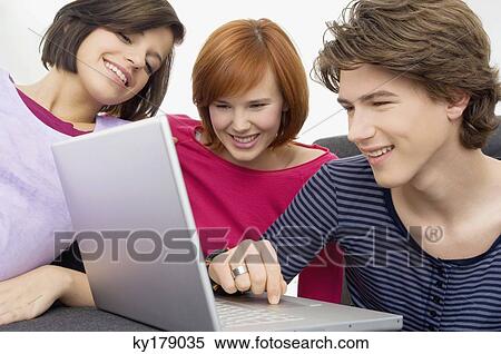 Close-up of two young women and a teenage boy looking at a laptop View Large Photo Image Stock Photography - Close-up of two young women and a teenage boy looking at a laptop. Fotosearch