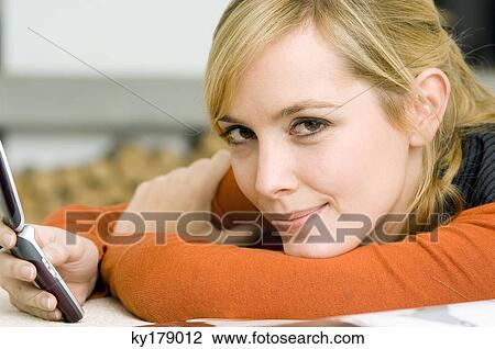 Stock Image - Portrait of a young woman holding a mobile phone and smiling. Fotosearch