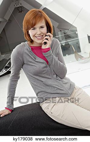 Portrait of a young woman using a mobile phone and smiling View Large Photo Image Stock Photo - Portrait of a young woman using a mobile phone and smiling. Fotosearch