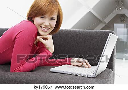 Portrait of a young woman using a laptop and smiling View Large Photo Image Stock Photo - Portrait of a young woman using a laptop and smiling. Fotosearch