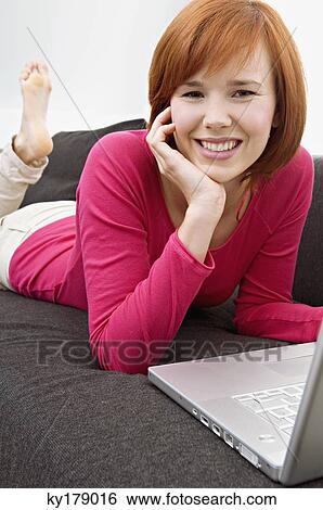 Portrait of a young woman using a laptop and smiling View Large Photo Image Stock Photograph - Portrait of a young woman using a laptop and smiling. Fotosearch