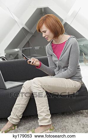 Side profile of a young woman sitting in front of a laptop and using a mobile phone View Large Photo Image Stock Image - Side profile of a young woman sitting in front of a laptop and using a mobile phone. Fotosearch