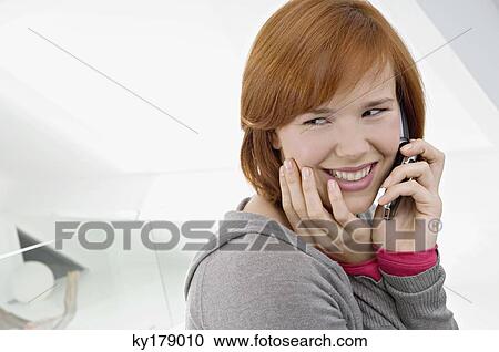 Side profile of a young woman using a mobile phone and smiling View Large Photo Image Stock Image - Side profile of a young woman using a mobile phone and smiling. Fotosearch
