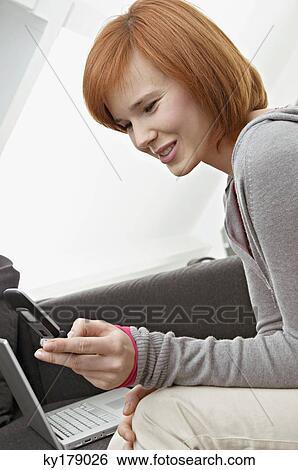 Side profile of a young woman using a mobile phone and smiling View Large Photo Image Stock Photograph - Side profile of a young woman using a mobile phone and smiling. Fotosearch