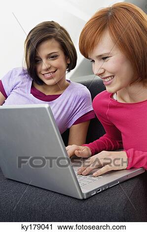 Two young women using a laptop and smiling View Large Photo Image Stock Image - Two young women using a laptop and smiling. Fotosearch