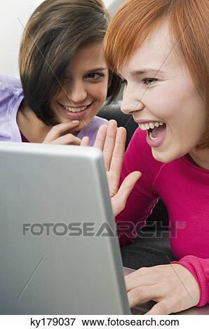 Two young women using a laptop View Large Photo Image Stock Photo - Two young women using a laptop. Fotosearch
