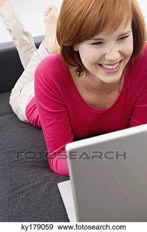 Young woman using a laptop and smiling View Large Photo Image Stock Photo - Young woman using a laptop and smiling. Fotosearch
