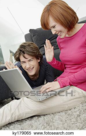 Stock Photography - Young woman with a teenage boy using a laptop. Fotosearch