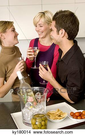 Two young women and a young man holding martini glasses View Large Photo Image Picture - Two young women and a young man holding martini glasses. Fotosearch