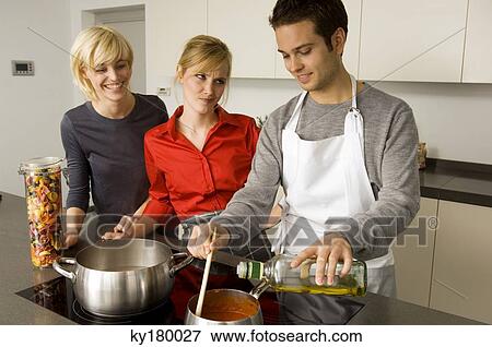 Two young women and a young man preparing food in the kitchen View Large Photo Image Stock Photo - Two young women and a young man preparing food in the kitchen. Fotosearch