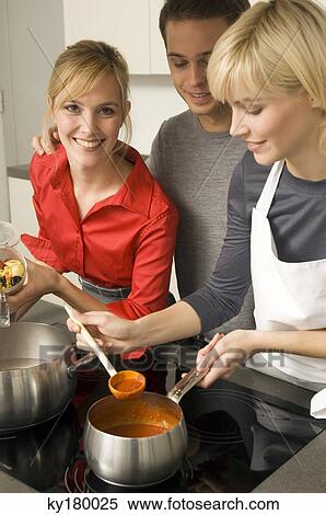 Two young women and a young man preparing food in the kitchen View Large Photo Image Stock Photography - Two young women and a young man preparing food in the kitchen. Fotosearch