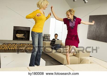 Two young women dancing with a young man using a laptop in the background View Large Photo Image Stock Photo - Two young women dancing with a young man using a laptop in the background. Fotosearch