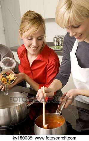 Stock Photography - Two young women preparing food in the kitchen. Fotosearch