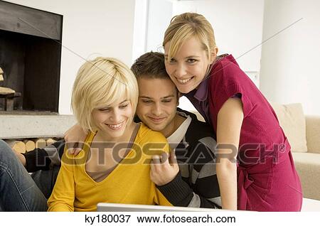Two young women with a young man in front of a laptop View Large Photo Image Stock Photo - Two young women with a young man in front of a laptop. Fotosearch