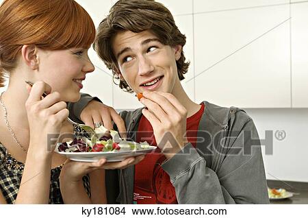Close-up of a teenage boy and a young woman eating salad View Large Photo Image Picture - Close-up of a teenage boy and a young woman eating salad. Fotosearch