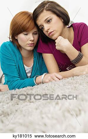 Close-up of two young women lying on a carpet and looking serious View Large Photo Image Stock Photography - Close-up of two young women lying on a carpet and looking serious. Fotosearch