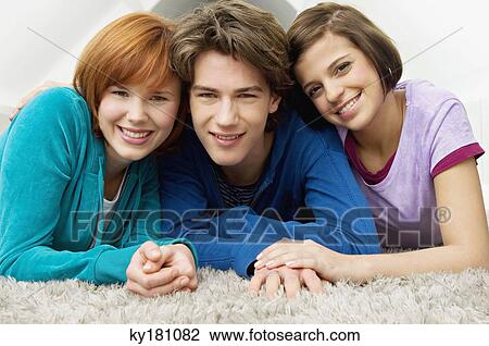 Stock Image - Portrait of a teenage boy smiling with two young women. Fotosearch