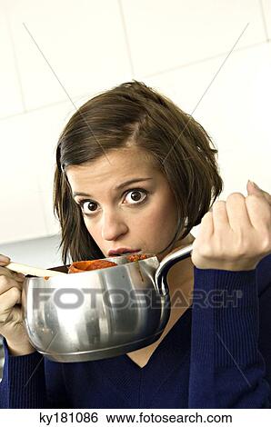 Portrait of a young woman holding a saucepan and looking surprised View Large Photo Image Stock Photograph - Portrait of a young woman holding a saucepan and looking surprised. Fotosearch