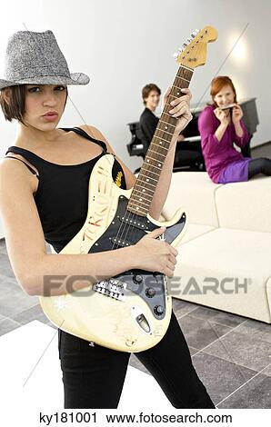 Portrait of a young woman playing a guitar View Large Photo Image Stock Image - Portrait of a young woman playing a guitar. Fotosearch