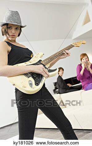 Portrait of a young woman playing a guitar View Large Photo Image Stock Photograph - Portrait of a young woman playing a guitar. Fotosearch