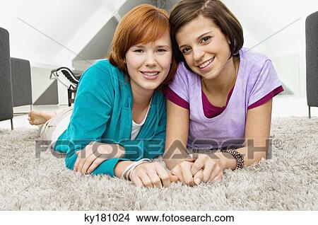 Portrait of two young women lying on a rug and smiling View Large Photo Image Picture - Portrait of two young women lying on a rug and smiling. Fotosearch
