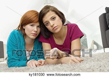 Portrait of two young women lying on a carpet and looking serious View Large Photo Image Stock Image - Portrait of two young women lying on a carpet and looking serious. Fotosearch
