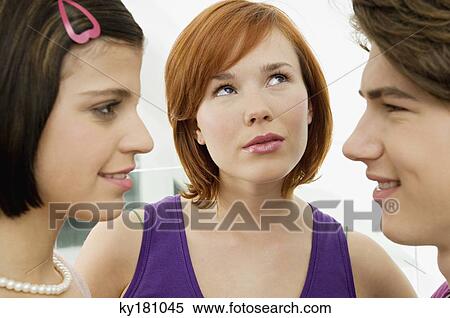 Stock Photography - Side profile of a teenage boy looking at a young woman with another young woman looking up. Fotosearch