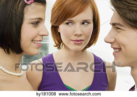 Stock Photo - Side profile of a teenage boy smiling with two young women. Fotosearch