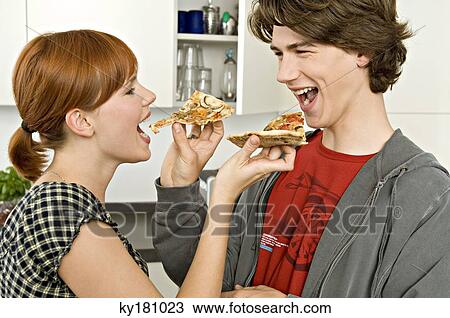 Side profile of a young woman and a teenage boy feeding pizza slices to each other View Large Photo Image Stock Image - Side profile of a young woman and a teenage boy feeding pizza slices to each other. Fotosearch