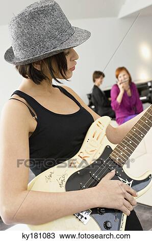 Side profile of a young woman playing a guitar View Large Photo Image Stock Image - Side profile of a young woman playing a guitar. Fotosearch