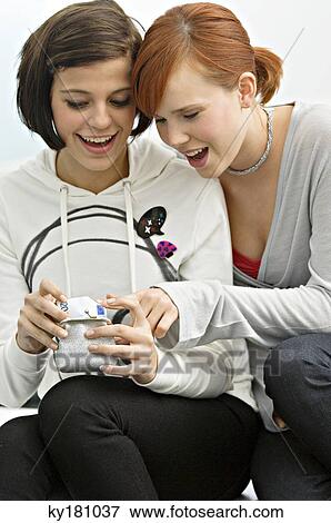 Two young women looking money in a change purse View Large Photo Image Stock Photo - Two young women looking money in a change purse. Fotosearch