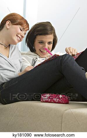 Young woman looking at her friend writing View Large Photo Image Stock Image - Young woman looking at her friend writing. Fotosearch
