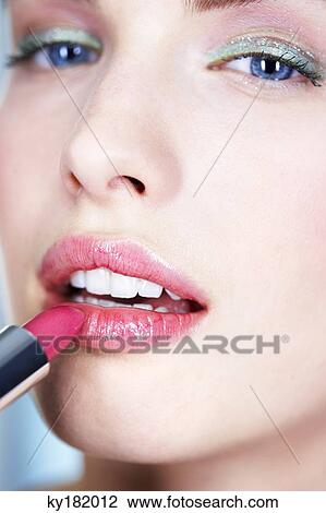 Portrait of young woman applying lipstick View Large Photo Image Stock Image - Portrait of young woman applying lipstick. Fotosearch