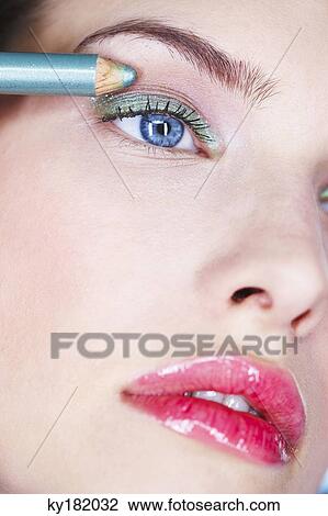 Stock Image - Young woman applying eyeliner. Fotosearch