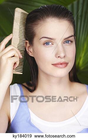 Young woman combing her hair View Large Photo Image Stock Photo - Young woman combing her hair. Fotosearch