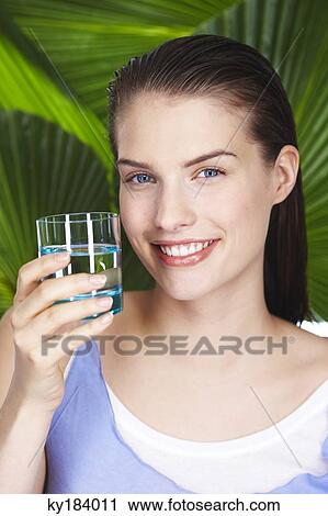 Young woman holding glass of water View Large Photo Image Stock Image - Young woman holding glass of water. Fotosearch