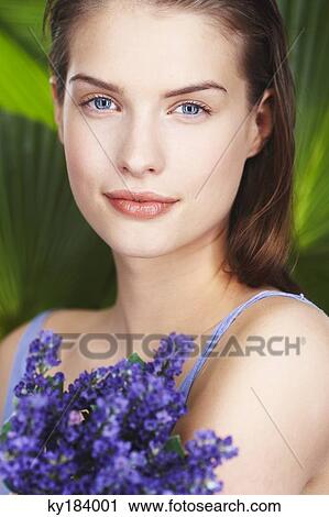 Stock Image - Young woman holding lavender sprigs. Fotosearch
